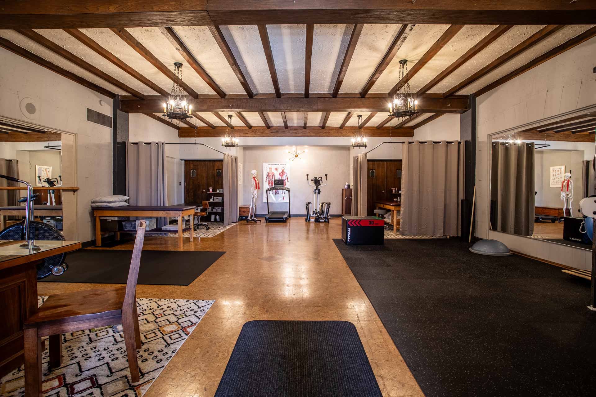 A wide angle photo of the MKE Physical Therapy clinic, showing the two private treatment areas, consultation desk and exercise areas