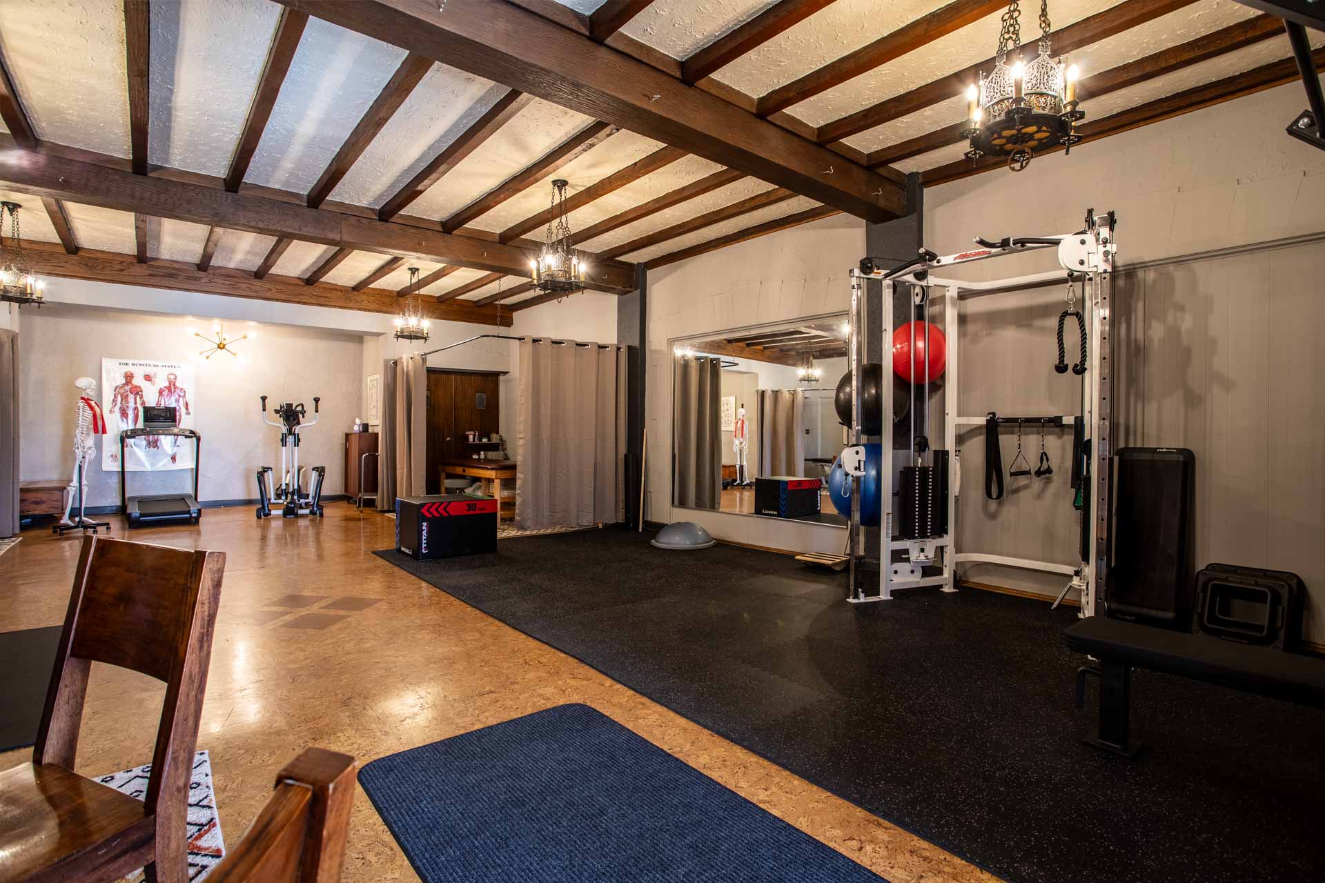 A wide angle photo of the MKE Physical Therapy clinic, showing a private treatment area, and exercise area with cable machine.