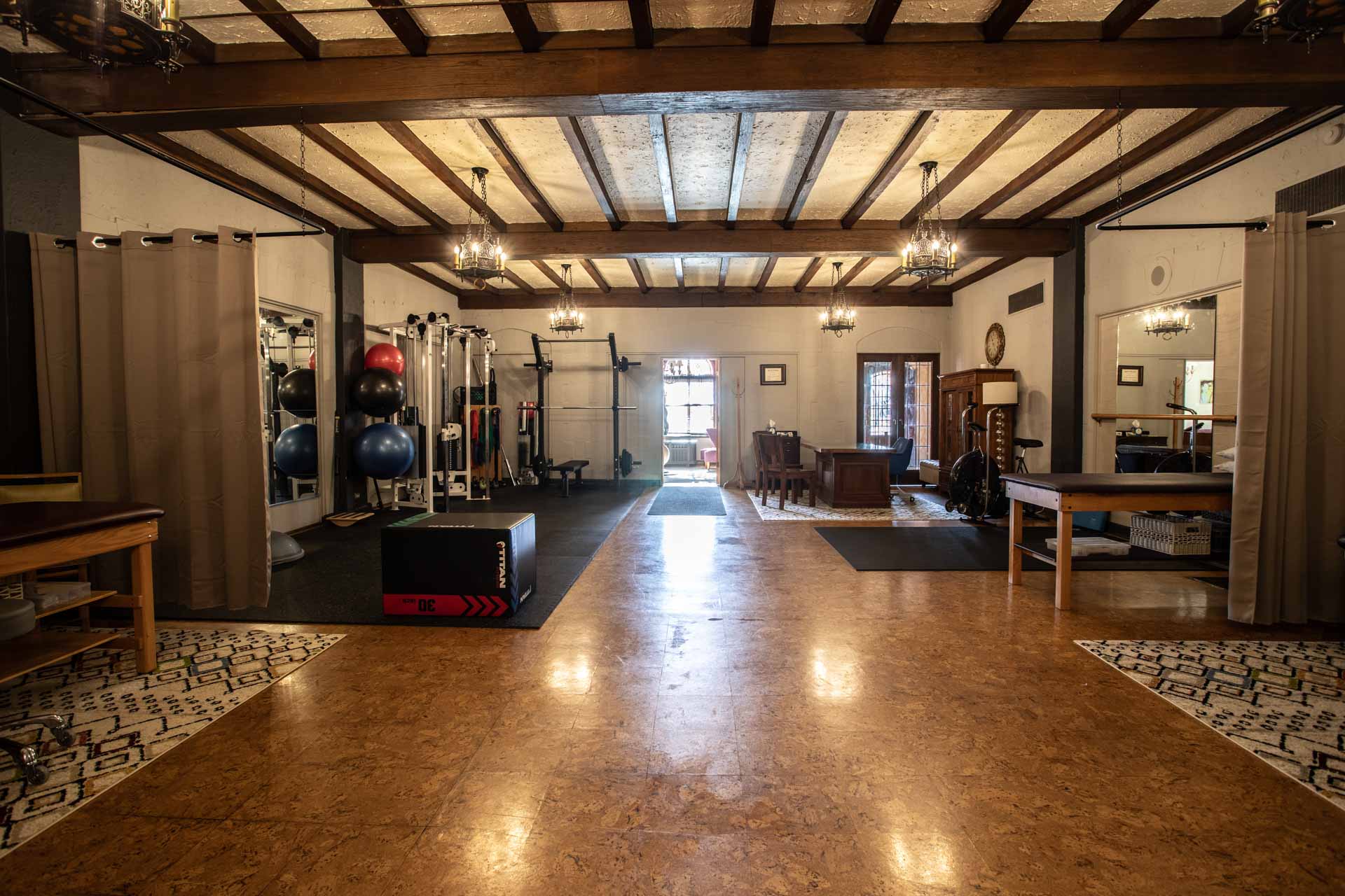 A wide angle photo of the MKE physical therapy clinic in Milwaukee, showing the private treatment areas in the foreground, and consultation and weight training areas in the background.